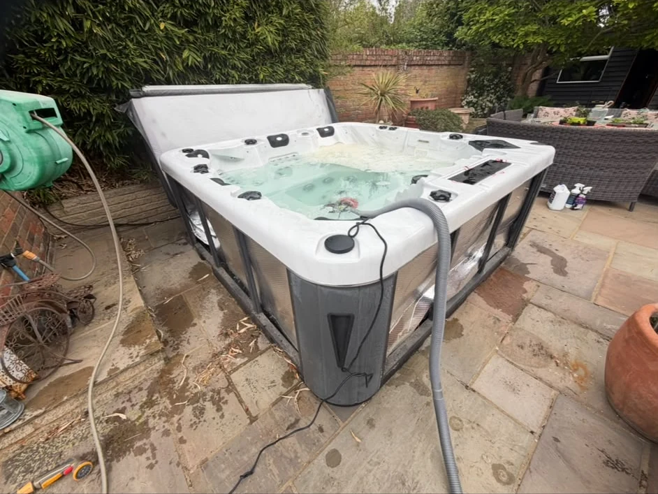 Compact garden hot tub with a service hose in the water