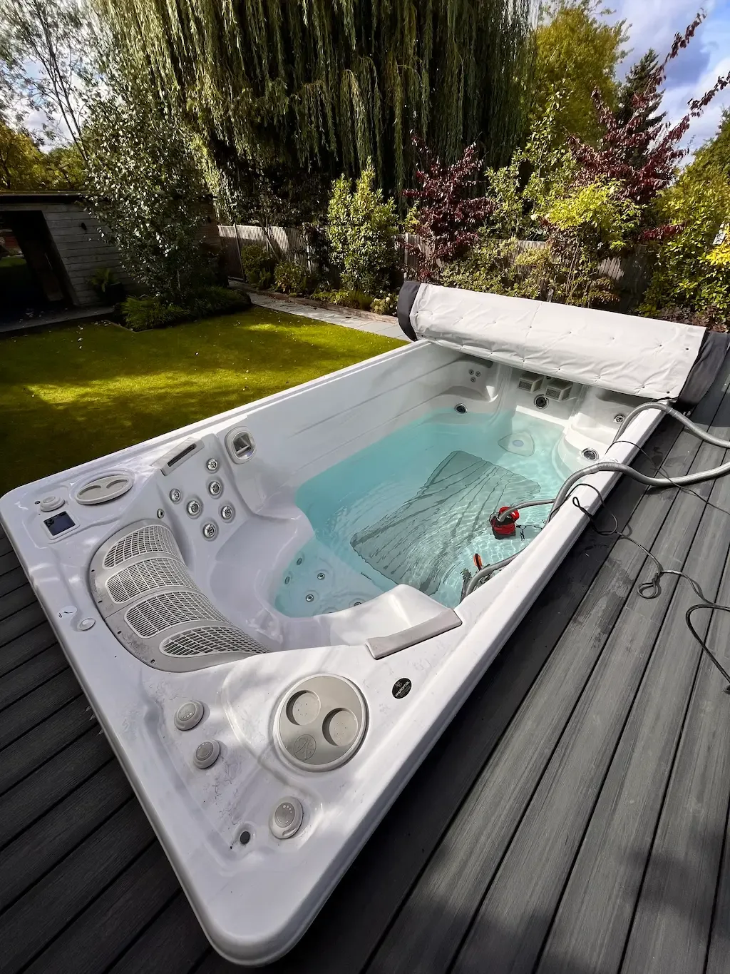 Filled swim spa with a pump hose inside